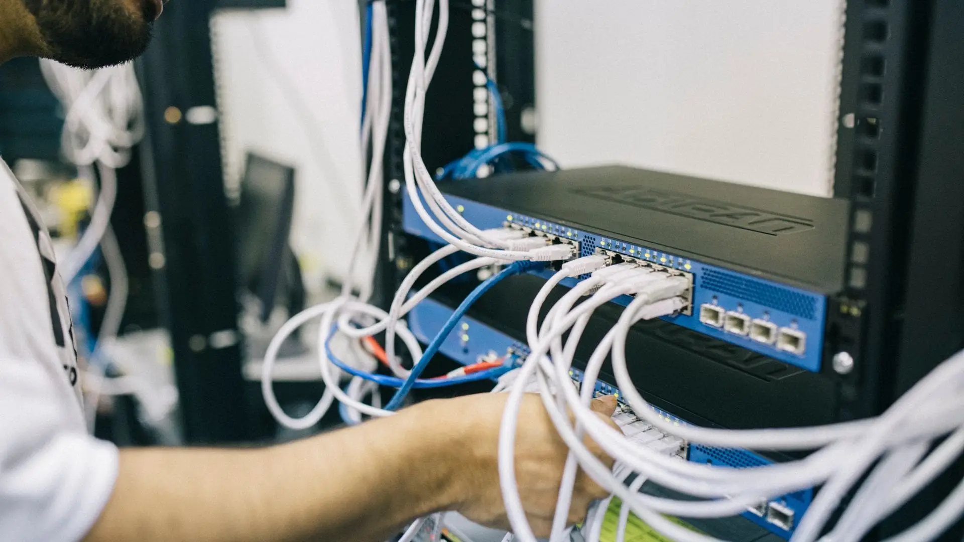 Technician connecting network cables to a switch in a communications rack