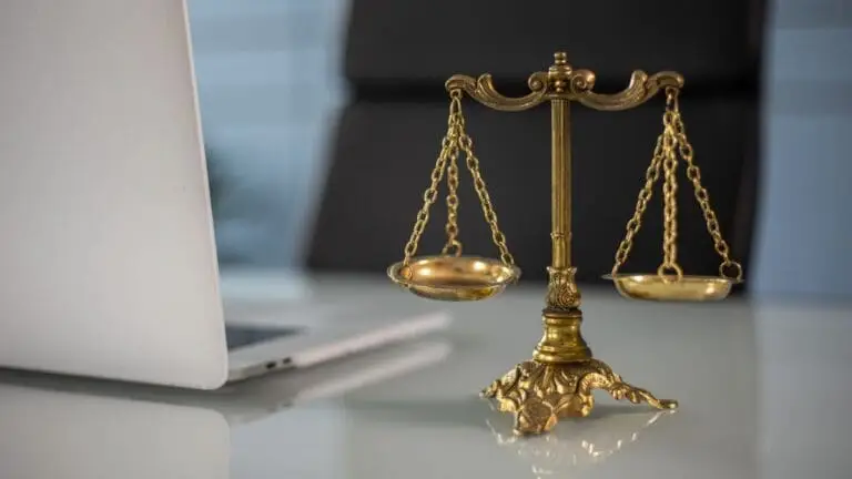 Brass scales of justice beside a laptop on a solicitor's desk in a law office