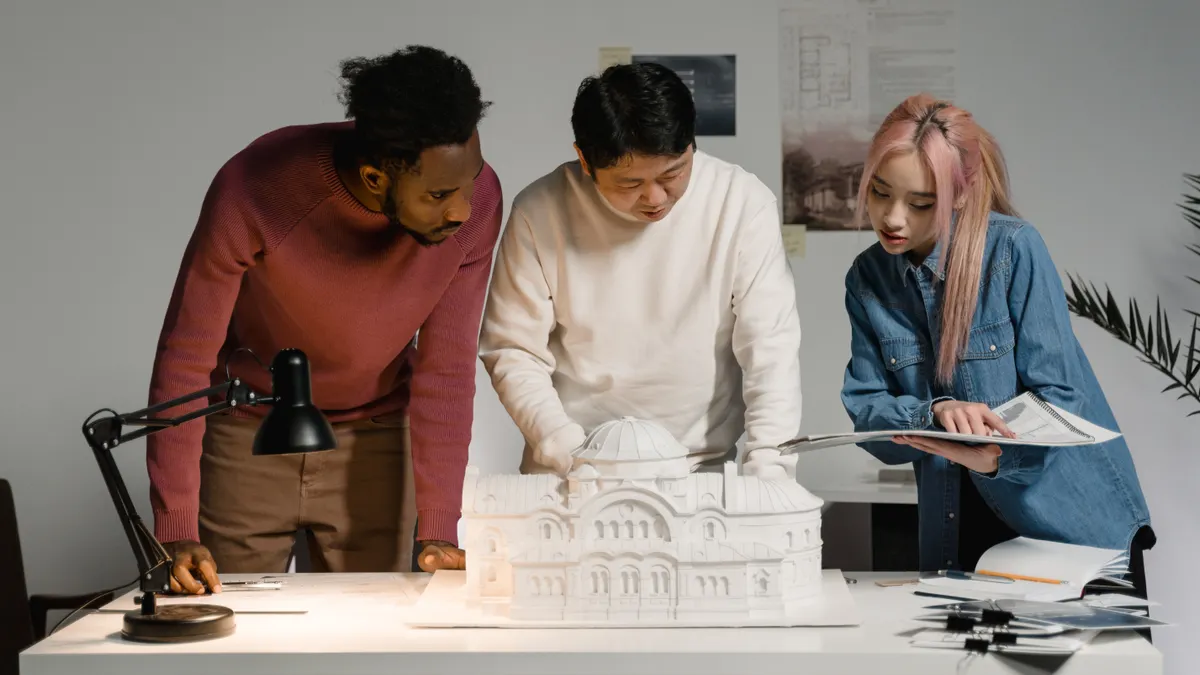 Architecture practice team reviewing a scale model in their studio, illustrating IT support cost per user for design practices