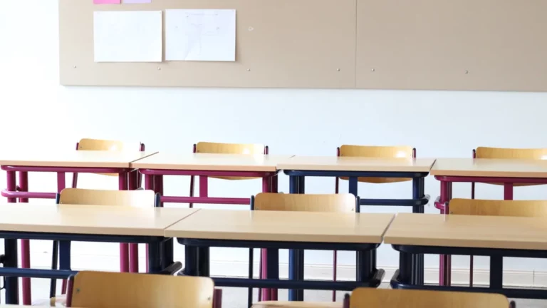 School Wi-Fi upgrade: an empty classroom with rows of wooden desks and chairs below a pinboard